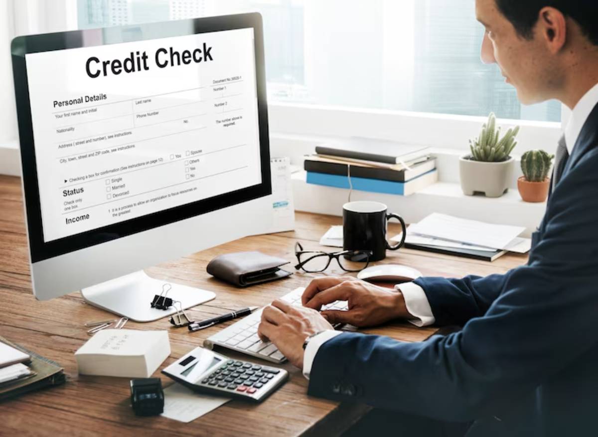 A businessman filling out a credit check form on a desktop, surrounded by office supplies and a scenic window view. 