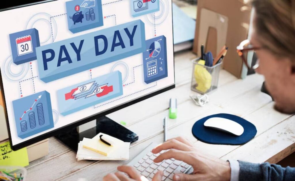 A close-up of hands typing on a keyboard in front of a computer screen displaying PAY DAY and various financial icons and graphs.