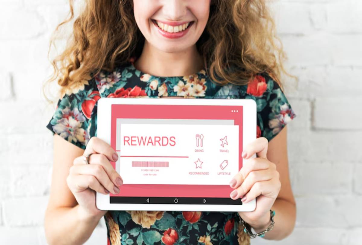  A woman in a floral shirt holds a tablet displaying a Rewards interface with icons for dining, travel, and recommendations.